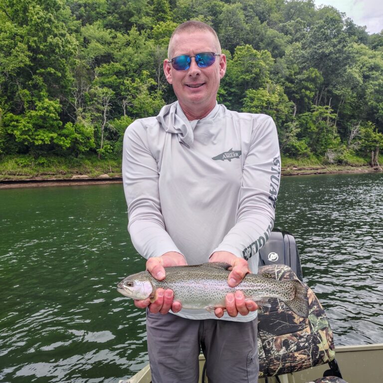 A client displaying a healthy rainbow trout caught while fly fishing the moving water on the Cumberland River tailwater in Burkesville, Kentucky.