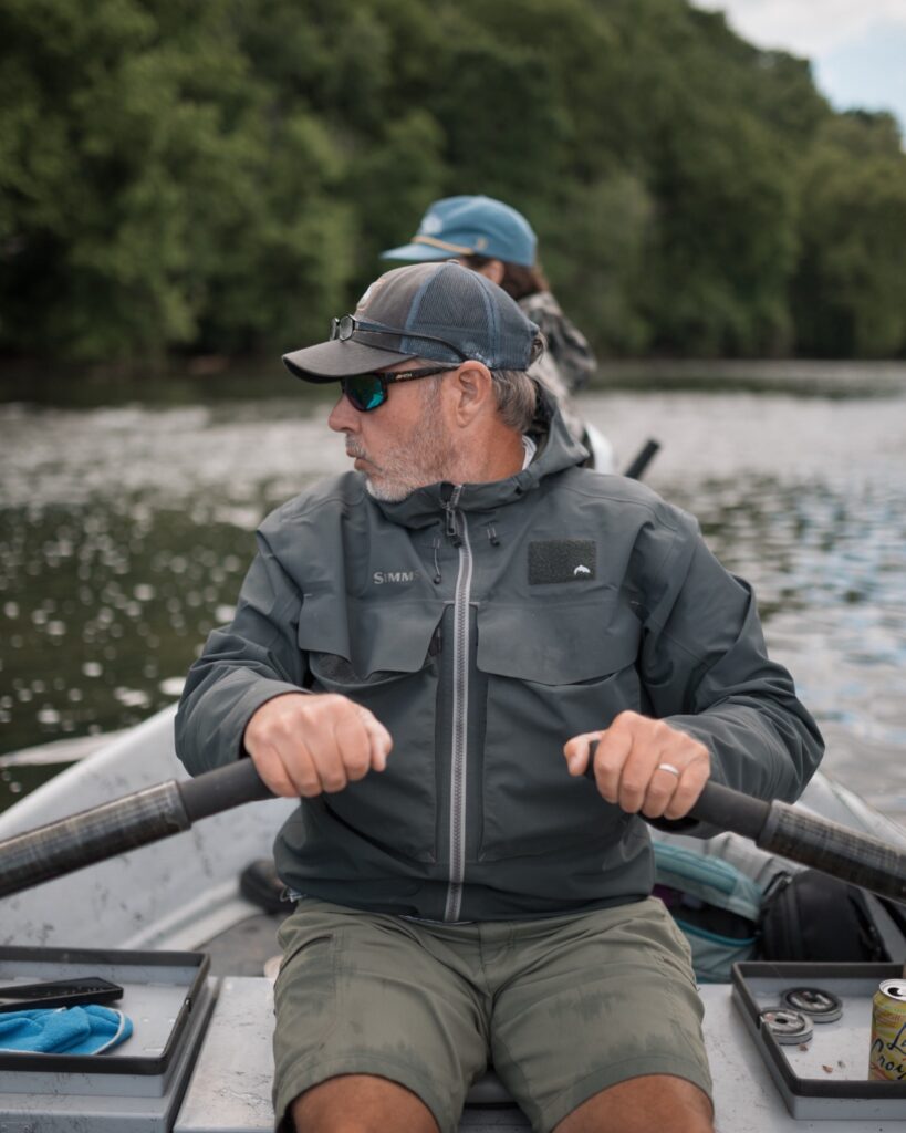 Captain Jeff Sharpe, a professional fly fishing guide, rowing a drift boat while guiding a trip on the scenic Holston river.