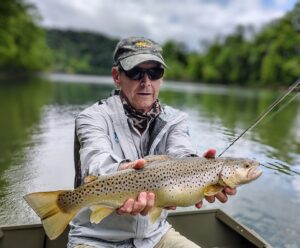 An angler holding a large, beautifully spotted brown trout caught while fly fishing on the Cumberland River.