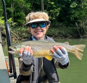 A young lady fly fishing client smiling while holding a beautiful Brown Trout caught on a guided boat trip on the Cumberland River.