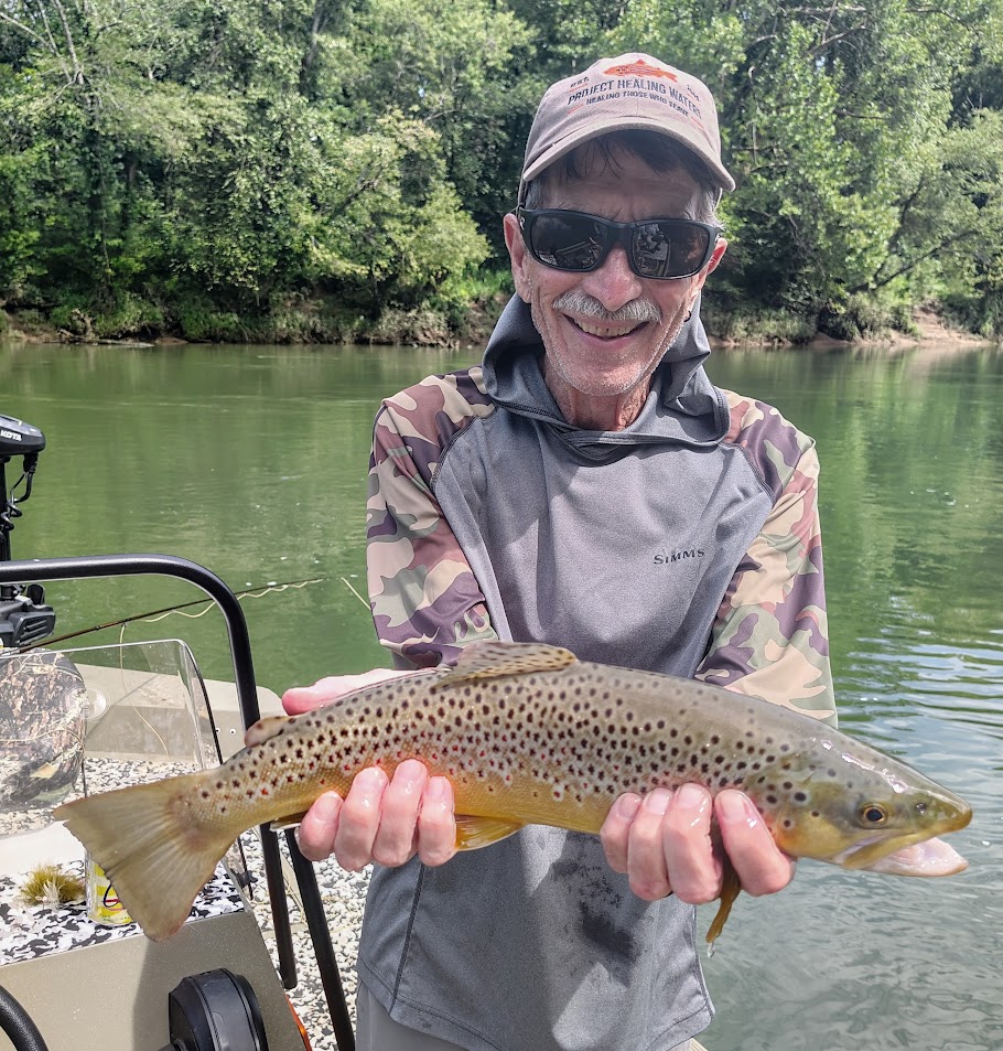 A client smiling while holding a massive trophy Brown Trout on a guided boat trip on the Cumberland River.