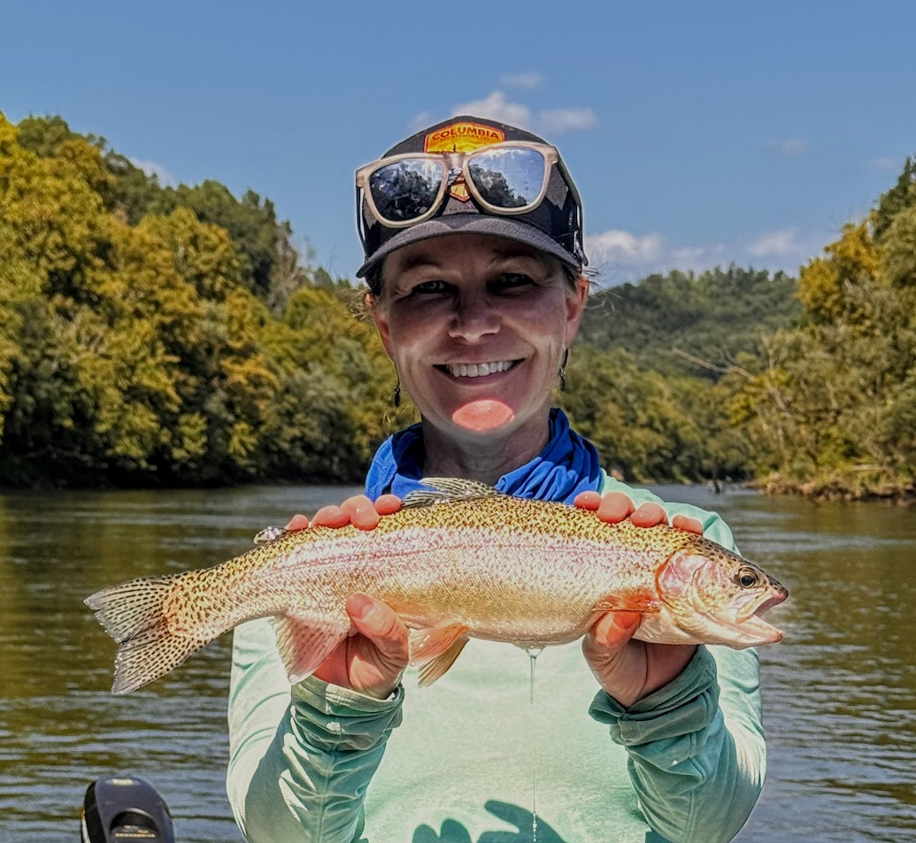A happy fly fishing client holding a vibrant Rainbow Trout caught on a guided boat trip on the Cumberland River.