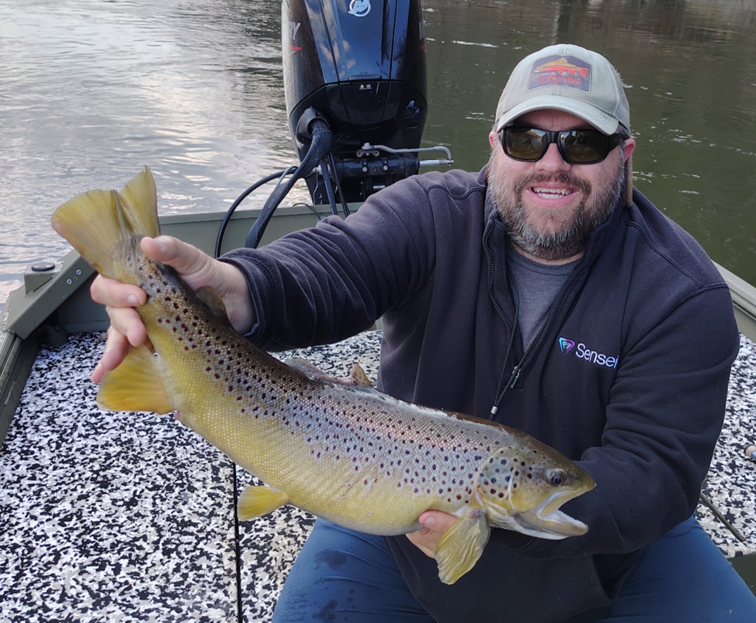 A fly fisherman holding a massive trophy Brown Trout on a boat during a Cumberland River guided trip.