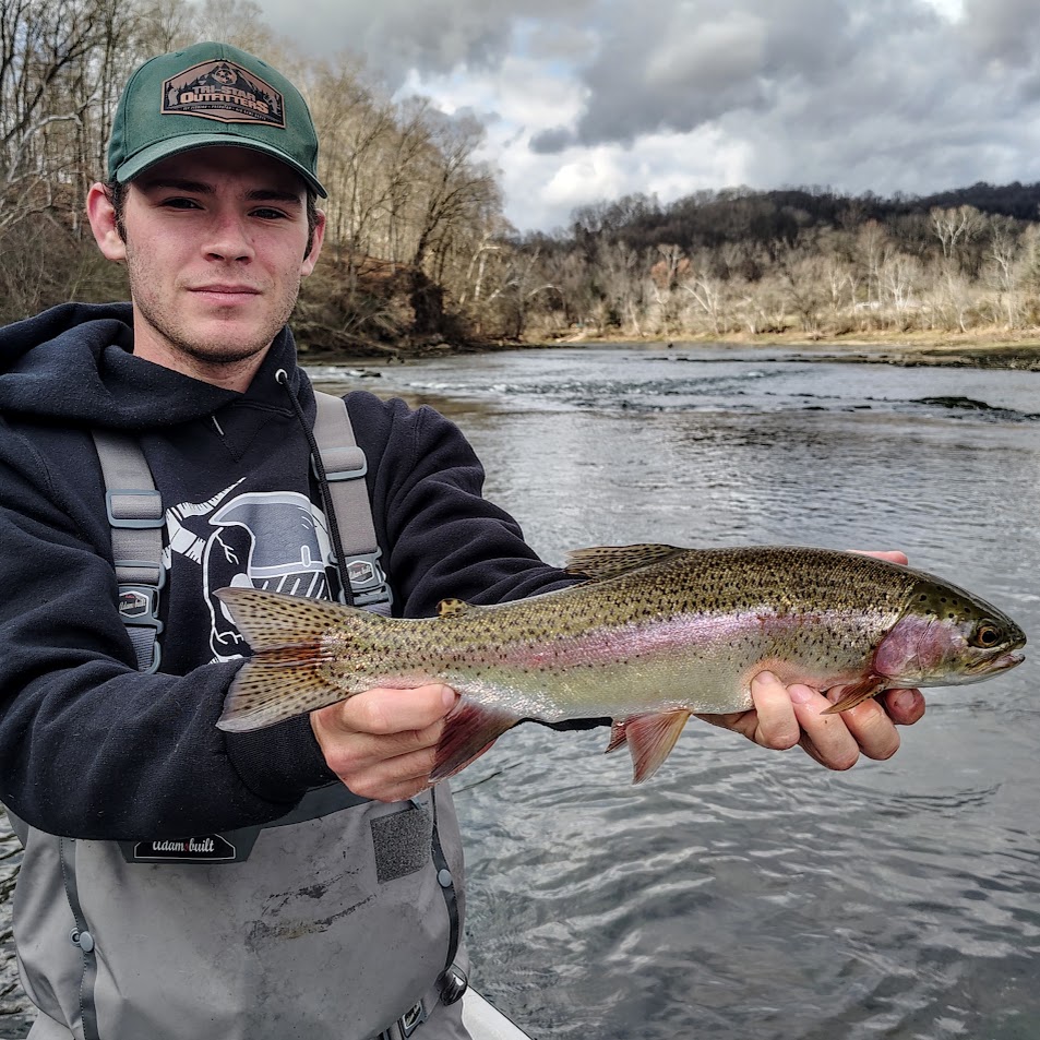 Young angler proudly holding a large rainbow trout caught while fly fishing on the Holston River.
