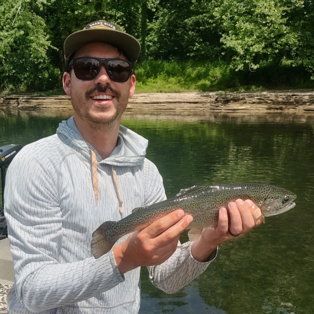 : A man holding a healthy rainbow trout caught on a fly rod on the Cumberland River in Burkesville, Kentucky.