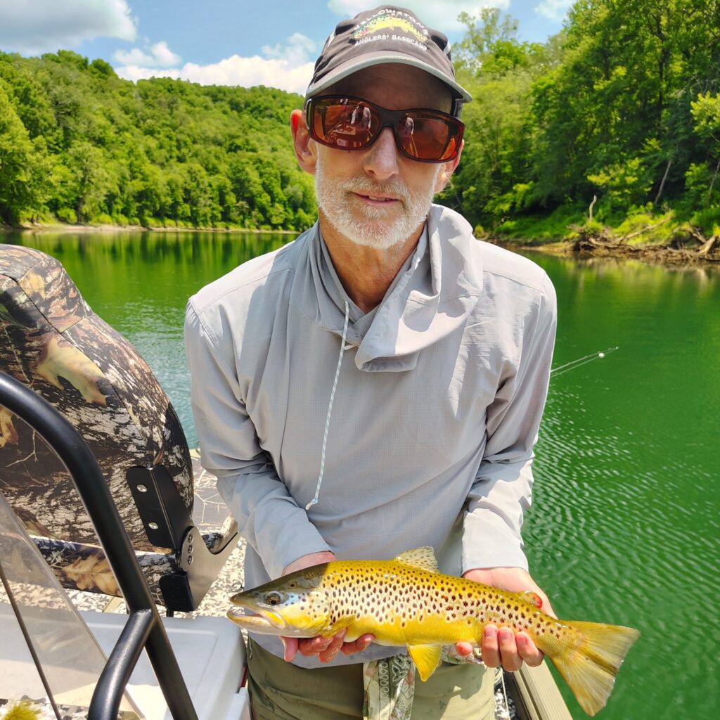 Angler holding a large brown trout caught on a fly rod on the Cumberland River in Kentucky.