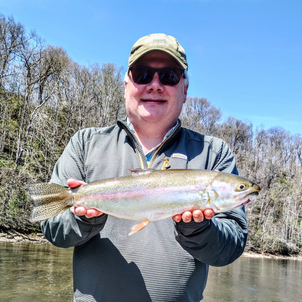 A happy client holding a vibrant rainbow trout caught on a dry fly during a hatch on the Holston River.