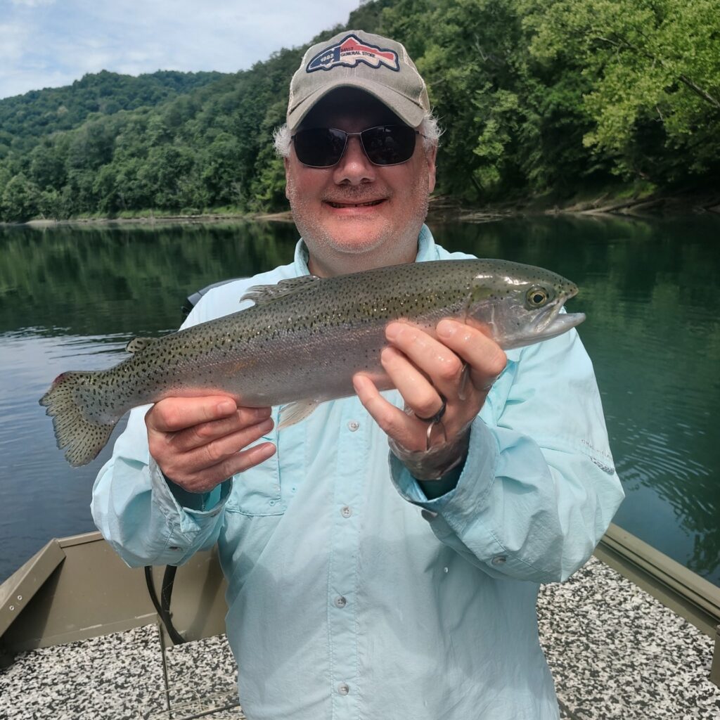 A happy client holding a large rainbow trout caught on the Cumberland River in Burkesville, Kentucky.