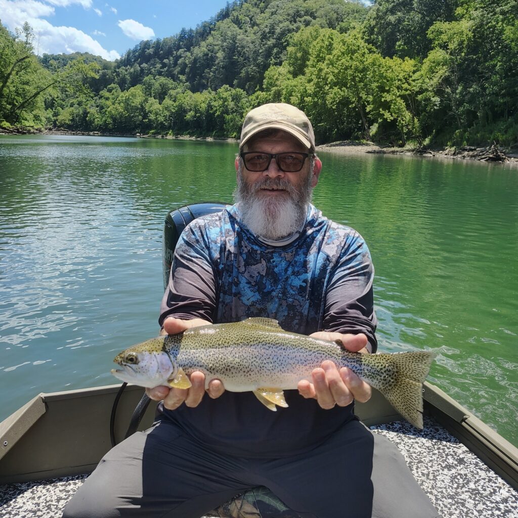 Angler holding a large, vibrant rainbow trout caught on a fly rod on the Cumberland River.