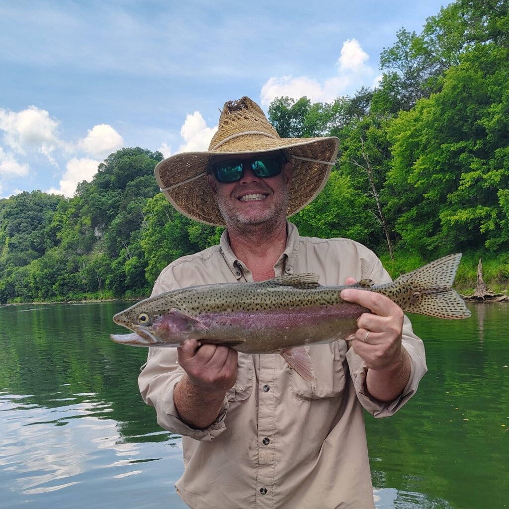 Angler holding a vibrant rainbow trout during a fly fishing trip on the Cumberland River.