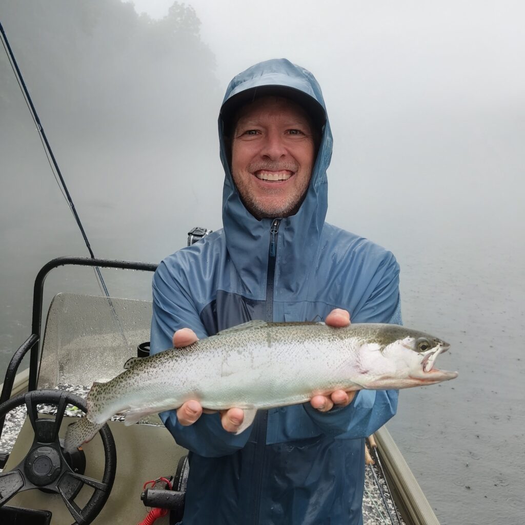 A happy angler holding a large, healthy rainbow trout caught on a fly rod on the Cumberland River in Burkesville, Kentucky.