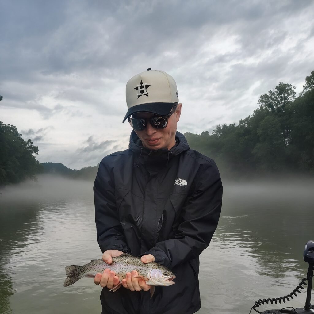 : A happy angler holding his first trout ever caught on a fly rod while fishing from a drift boat on the Cumberland River.