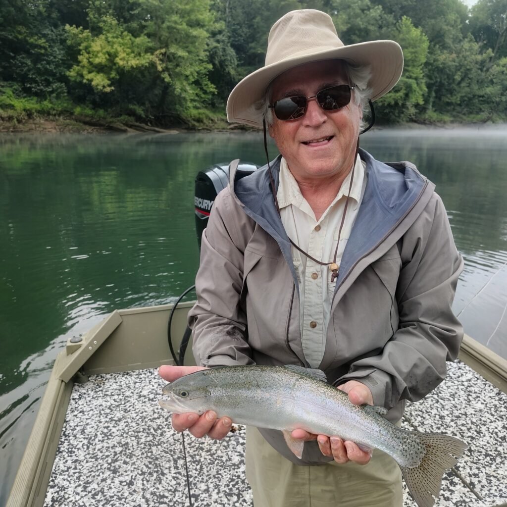 A client holding a vibrant rainbow trout caught on a hopper-dropper setup on the Cumberland River in Burkesville, Kentucky.