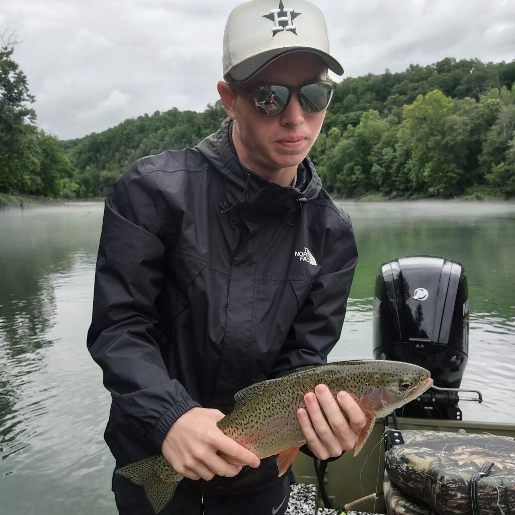 A happy angler holding a beautiful rainbow trout caught during a summer fly fishing trip on the Cumberland River.