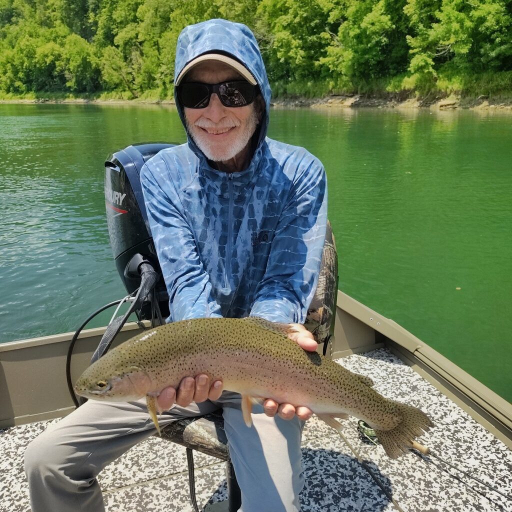 A happy angler holding a large, healthy rainbow trout caught on a fly rod on the Cumberland River in Burkesville, Kentucky.