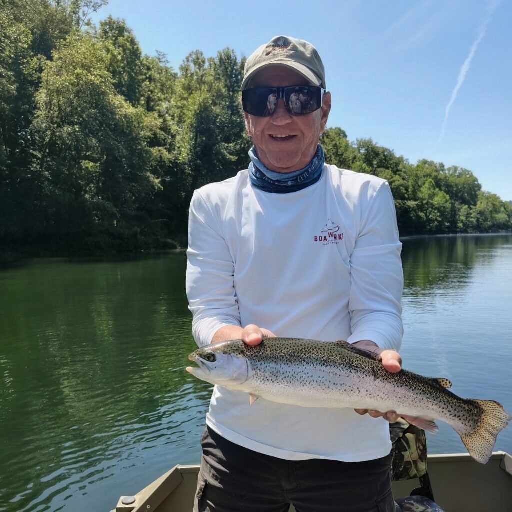 A client holding a vibrant rainbow trout on a guided fly fishing trip on the Cumberland River in Burkesville, Kentucky