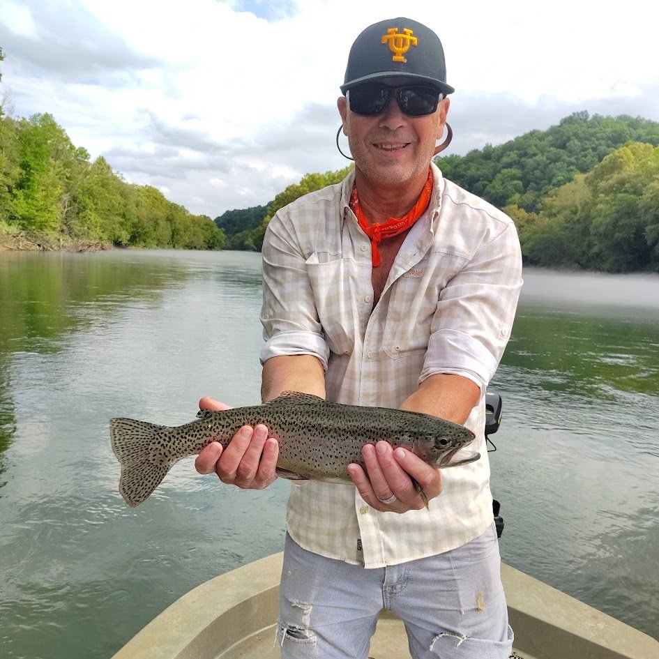 Angler holding a healthy Cumberland River rainbow trout caught on a drift boat near Burkesville, Kentucky