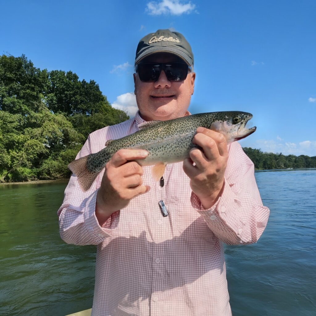 An angler holding a freshly caught rainbow trout on a guided fly fishing trip along the Cumberland River in Burkesville, Kentucky