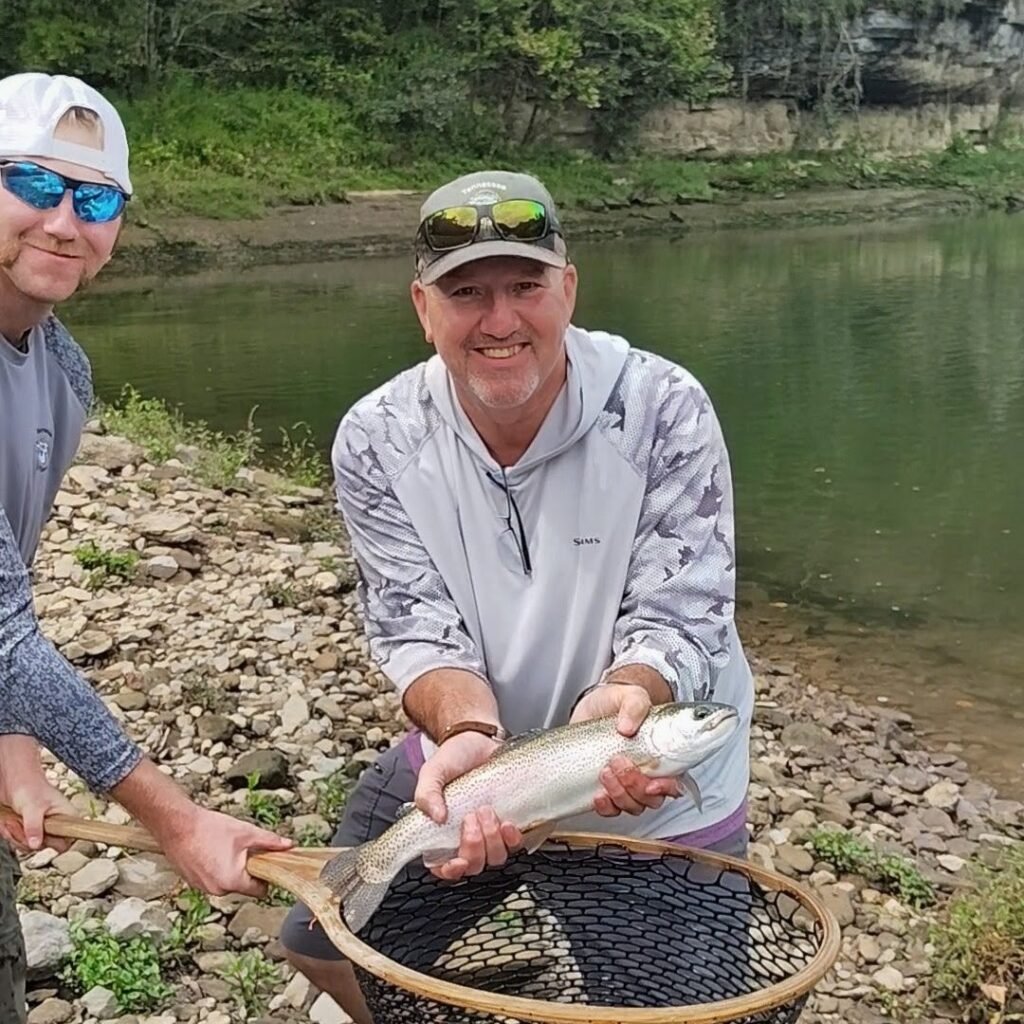 Father and son holding a rainbow trout on a guided fly fishing trip on the Cumberland River in Burkesville, Kentucky