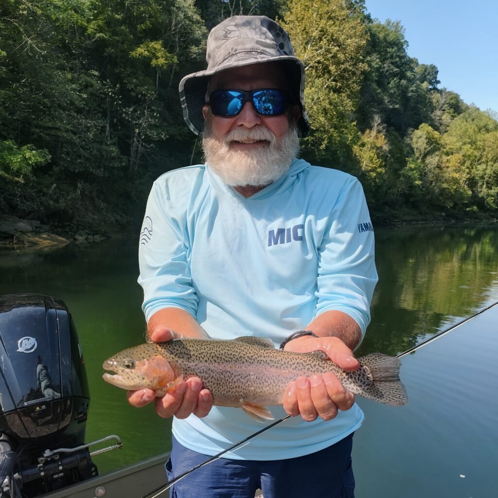 Smiling angler holding a vibrant rainbow trout caught on a dry fly during a guided trip on the Cumberland River in Burkesville, Kentucky