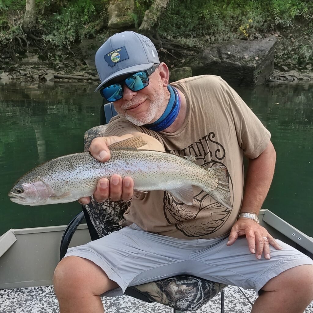 Angler holding a hopper-eating rainbow trout on a guided fly fishing trip on the Cumberland River in Burkesville, Kentucky