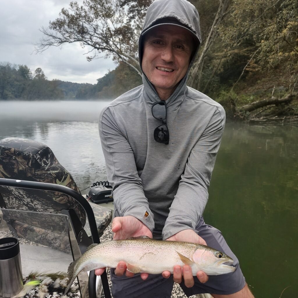 Angler holding a vibrant rainbow trout during an overcast guided fly fishing trip on the Cumberland River in Burkesville, Kentucky.