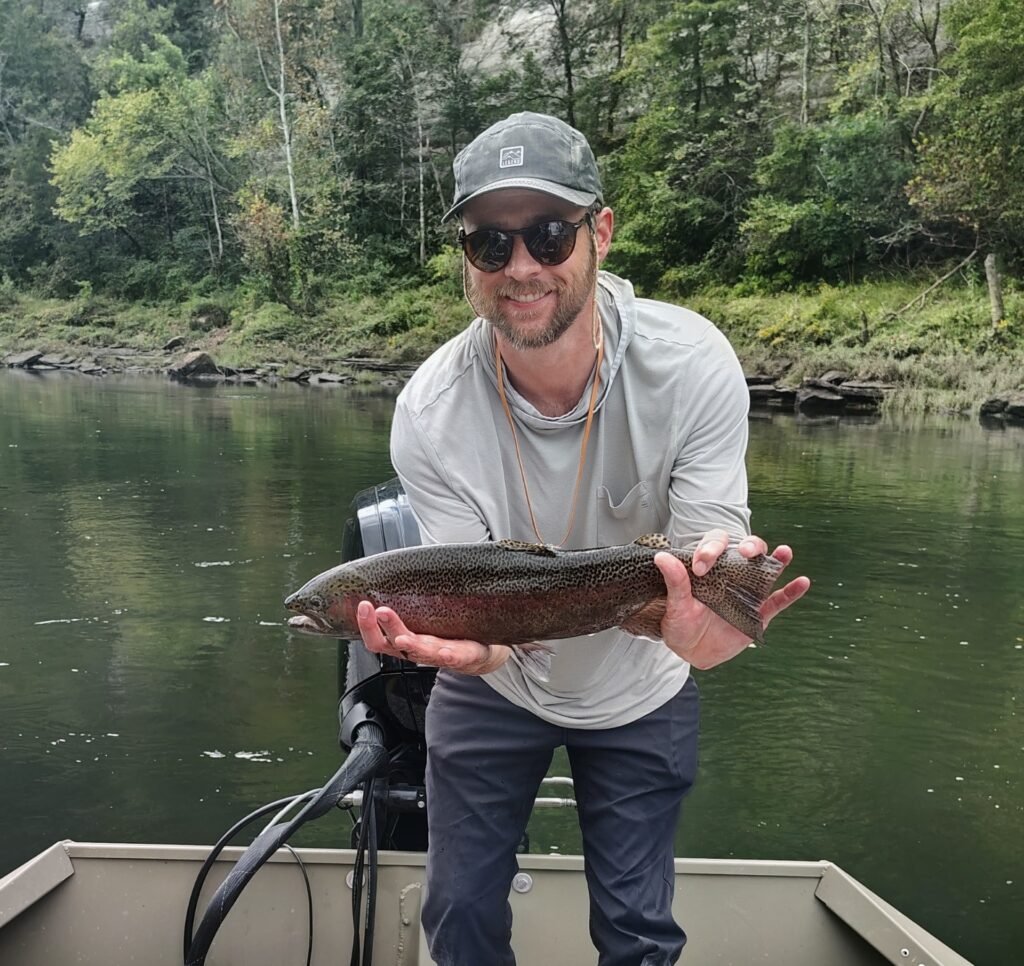 An angler holding a heavily colored rainbow trout caught on the Cumberland River.