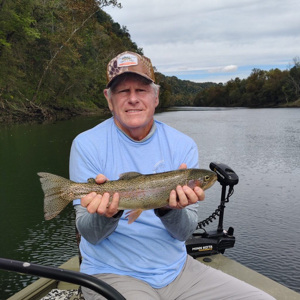 An angler holding a vibrant rainbow trout caught on the Cumberland River in Burkesville, Kentucky.