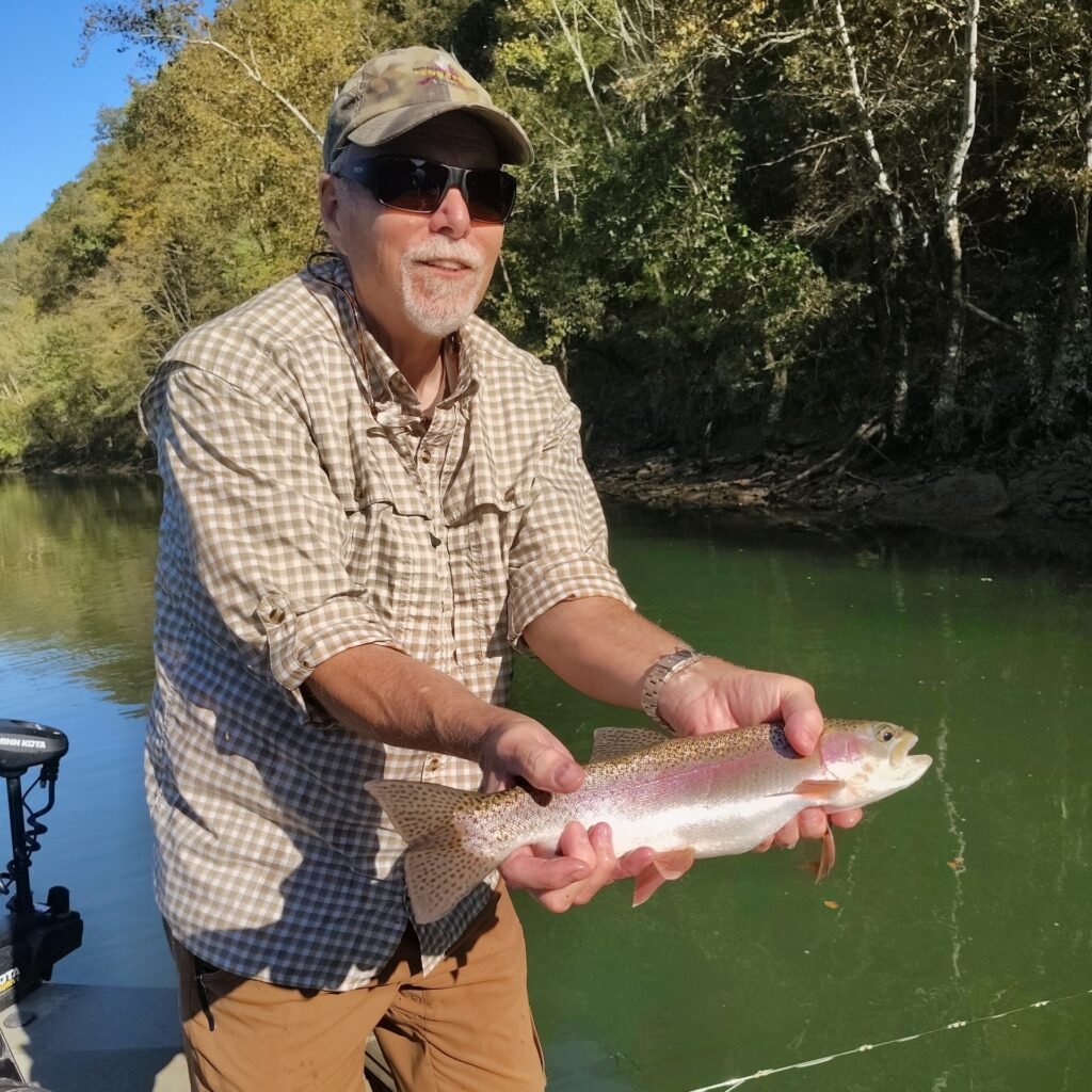 Angler holding a vibrant rainbow trout during a guided fly fishing trip in Burkesville, Kentucky.
