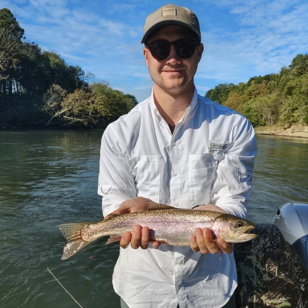 A smiling angler holding a quality rainbow trout on a guided fly fishing trip on the Cumberland River.