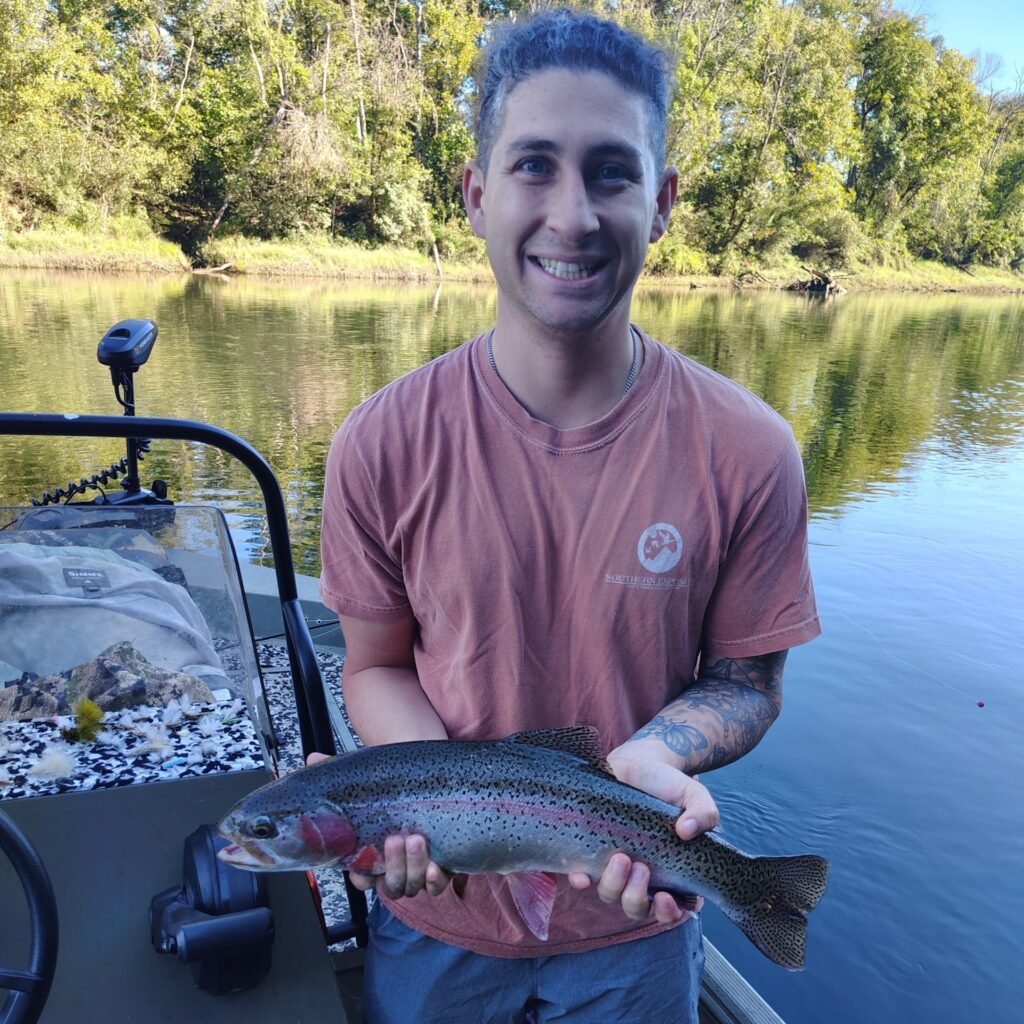 An angler holding a vibrant, stunning rainbow trout caught during a guided fly fishing trip on the Cumberland River.